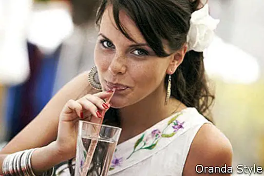 dievča pije vodu zo pohára slamkou