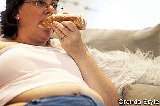 Overvektig kvinne som slapper av på sofaen