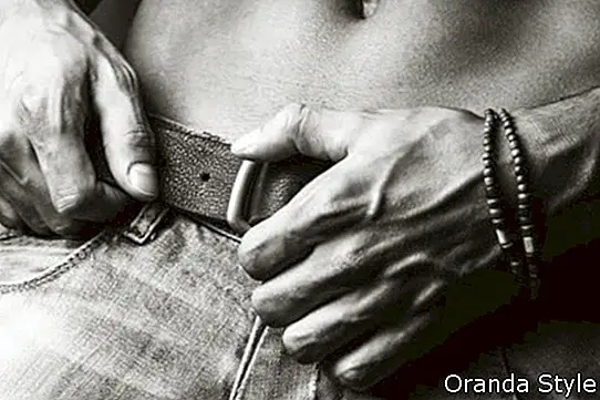 Svalnatý mladý sexy chlap pózuje ve studiu v džínách a nahý trup