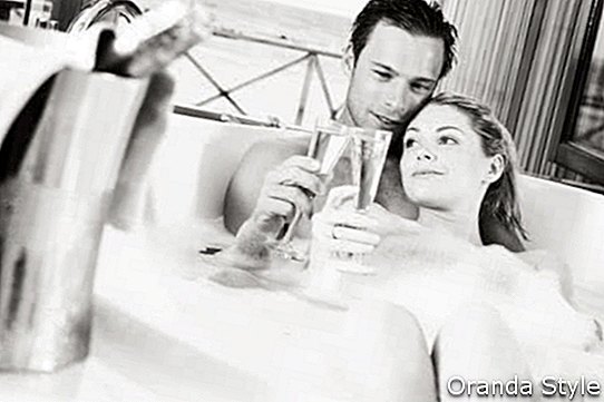Pāris atpūšas vannā kopā dzerot šampanieti