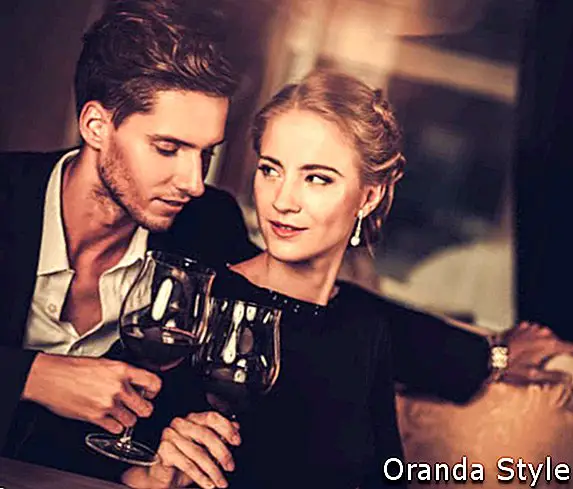 Vakre, unge par med glass vin i luksuriøst interiør