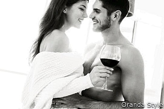 หนุ่มสาวผู้มีความสุขอ่อนโยนดื่มไวน์แดงด้วยกันที่บ้าน