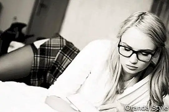 Seksualios protingos blondinės akiniai skaito knygą ant lovos