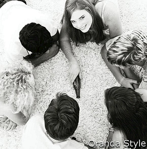 Grupo de amigos tumbados en el suelo y jugando a girar la botella