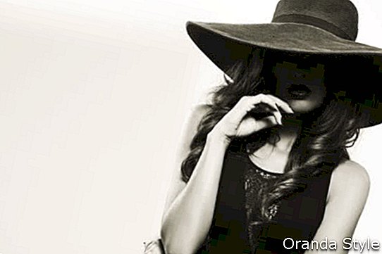 Krásná mladá žena nosí letní černý klobouk s velkým okrajem