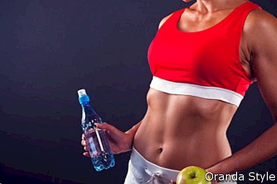 Фитнес девушка держит яблоко и воду