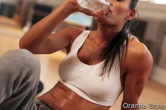 Fitnesa sieviete dzer ūdeni no pudeles