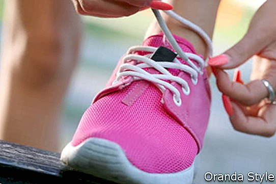 Läufermädchen, das rosa Schuhe bindet