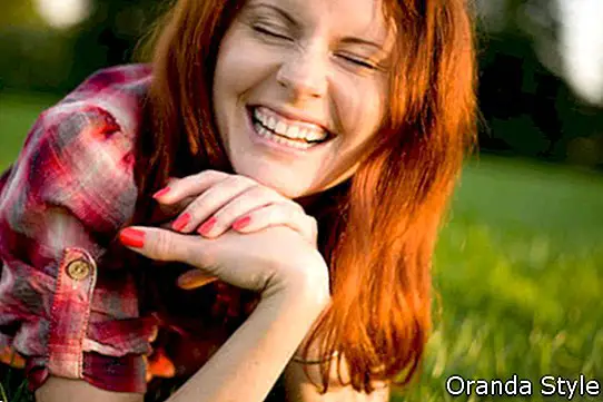 Млада щастлива жена, отпускаща се на зелена трева