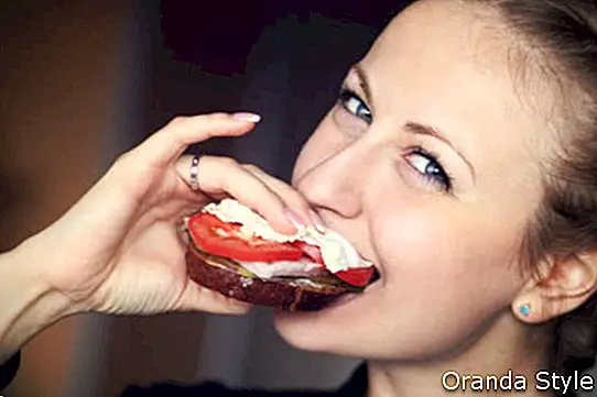 Mujer comiendo sandwich con tomate y mozzarella