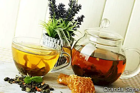 Šálka ​​a čajník zeleného čaju s medom na stole