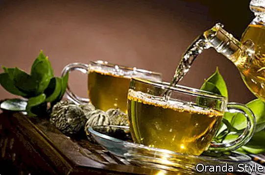 pohár čaju tečie zeleným čajom v šálke