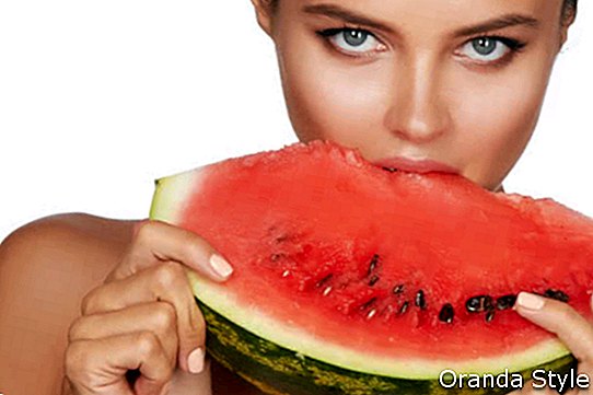 Vakker sexy brunette kvinne som spiser vannmelon