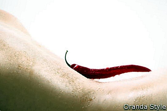 Røde varme chilipepper som ligger på en naken kropp av en kvinne