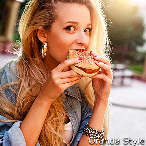 mujer comiendo hamburguesa con queso