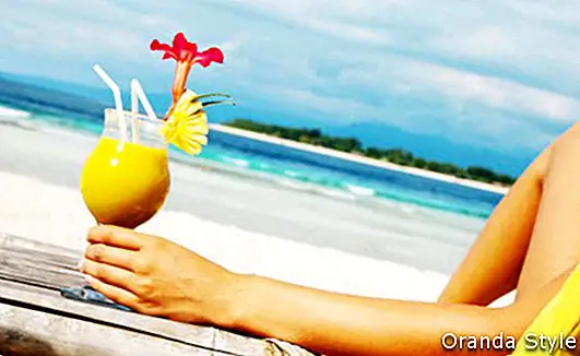 ženska ruka koja drži piće na plaži