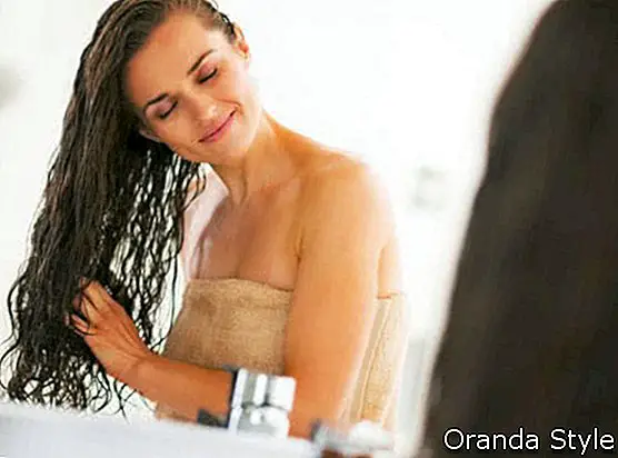 אישה צעירה מאושרת עם שיער רטוב בשירותים