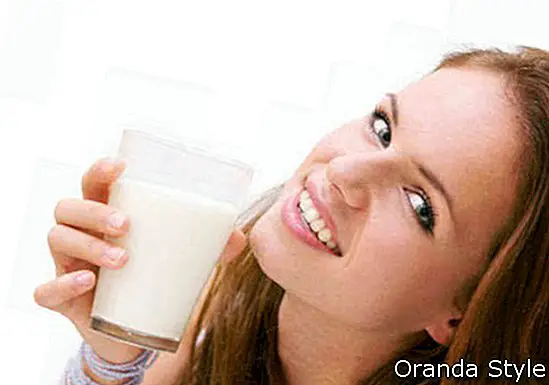 jauna skaista sieviete ar glāzi piena