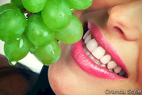 Wanita tersenyum dan anggur hijau