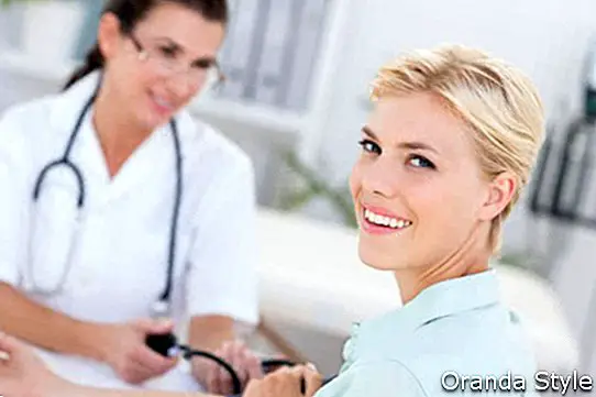 Doktor s krevní tlak její usmívající se pacient v ordinaci
