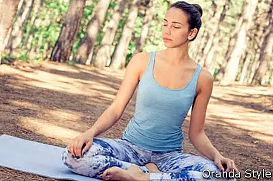 Lepa vesela mlada ženska meditira počet jogo na prostem v poletnem jesenskem parku