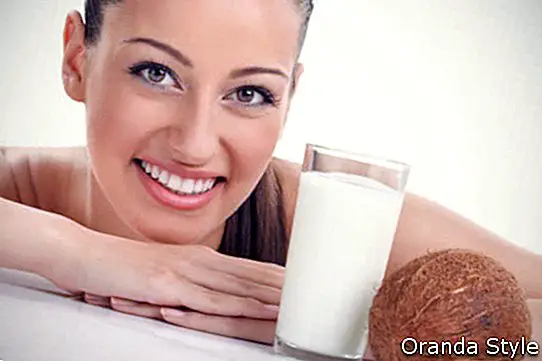 Nasmejana ženska in kokosov mlečni kozarec
