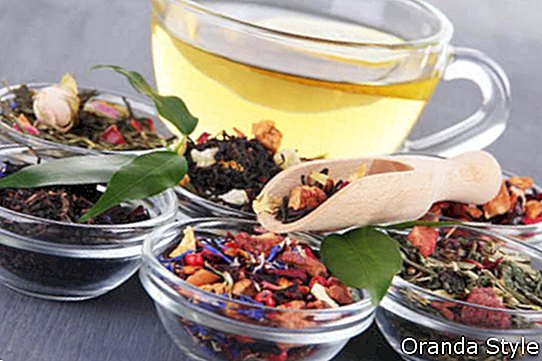 Tasse Tee mit aromatischem trockenem Tee in den Schüsseln auf hölzernem Hintergrund