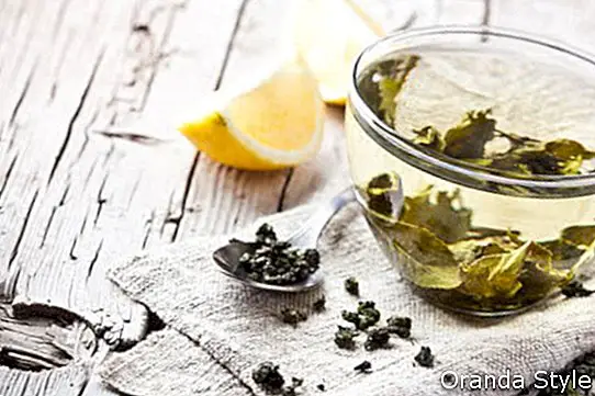 šálka zeleného čaju a citróna na rustikálnom drevenom stole