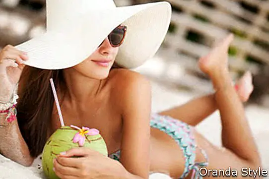 Красивая женщина расслабляющий на райском пляже с кокосом