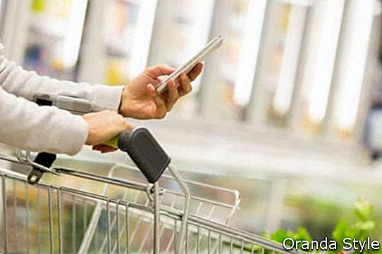 Moteris, naudodama mobilųjį telefoną, apsipirkdama prekybos centre