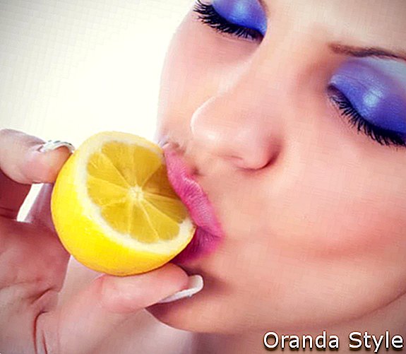 Wanita muda makan lemon