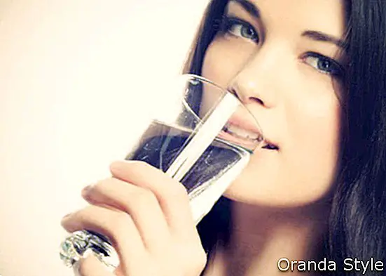 Hermosa mujer joven bebiendo un vaso de agua