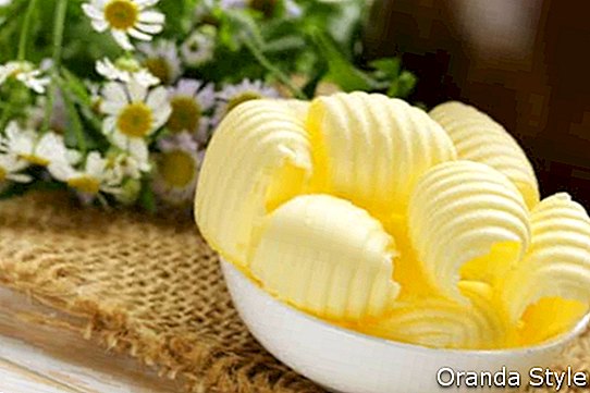 एक सफेद कटोरे में ताजा पीला डेयरी मक्खन