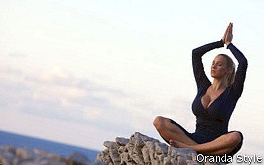 menina meditando sobre a rocha