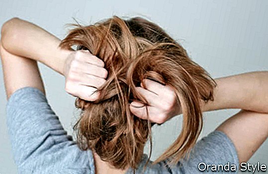 Tonårig flicka för ung kvinna som drar sitt långa ljusa hår på vit bakgrund
