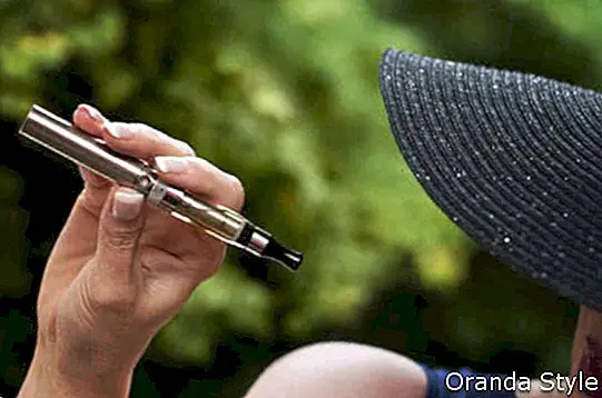 आउटडोर में ई-सिगरेट के साथ फैशन महिला