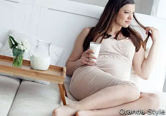 Σπίτι πορτρέτο της εγκύου γυναίκας που κατέχουν το ποτήρι γάλα