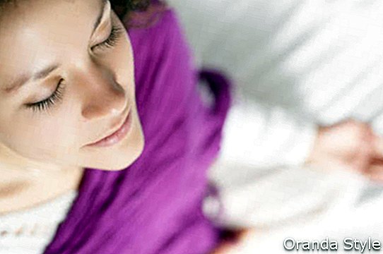 Ung vakker kvinne som gjør meditasjon på sengen