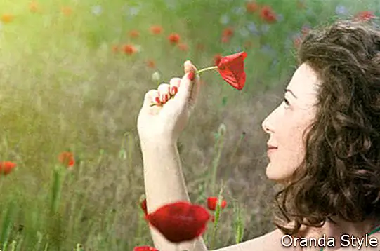 Kvindens hånd holder en valmueblomst ved aftensolen
