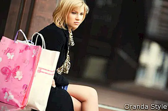 mujer joven triste con bolsas de compras