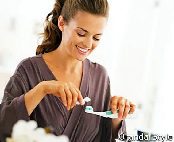 Glückliche Frau, die Zahnpasta vom Rohr zusammendrückt