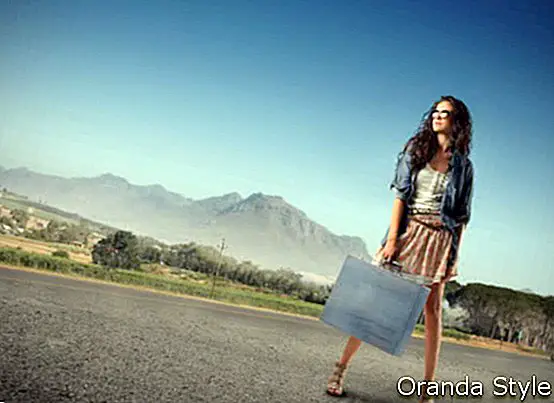 Ung kvinne som bærer en handlepose som står på en gate