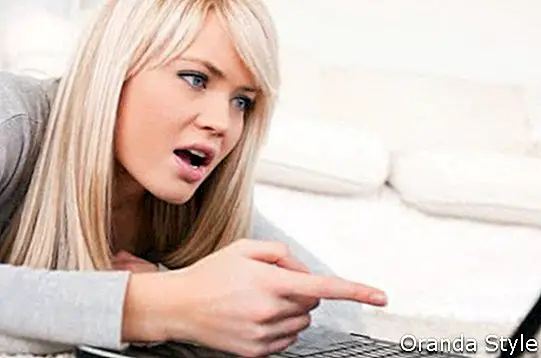 Recht blonde Frau frustriert mit ihrem Computer, der auf einem Teppich im Wohnzimmer liegt