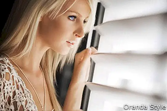 smuk blond kvinde kigger gennem vinduet