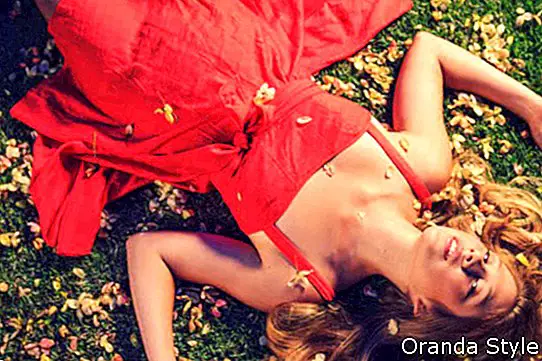 Piękna młoda kobieta, leżąc na trawie z kwiatami