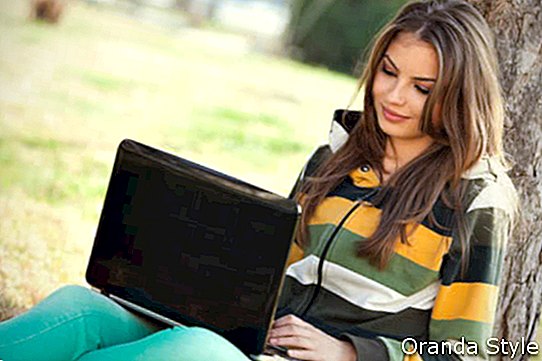 אישה צעירה עם מחשב נייד נרגע בפארק