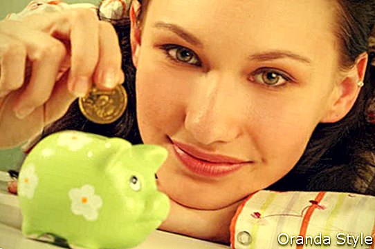 mujer joven poniendo una moneda en una caja de dinero verde