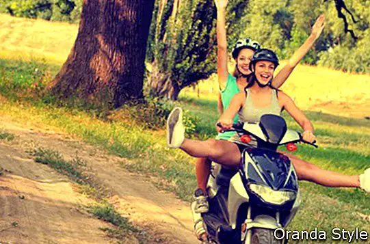 Divas pusaugu meitenes, braucot ar motociklu uz laukiem