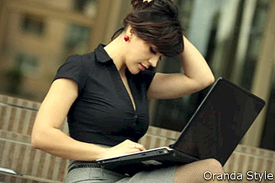 Lijepa poslovna žena koja koristi prijenosno računalo na otvorenom