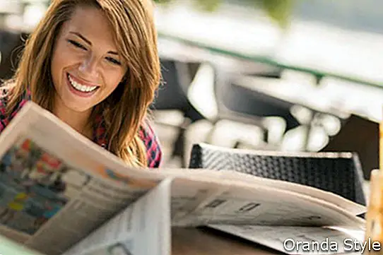 jauna brunetė mėgaujasi kava ir skaito laikraščius